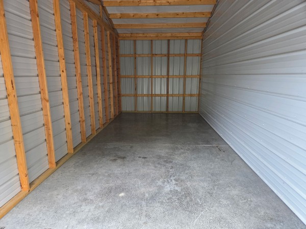 Interior of a large 10x25 storage unit showing exposed wood framing, metal walls, and a wide concrete floor